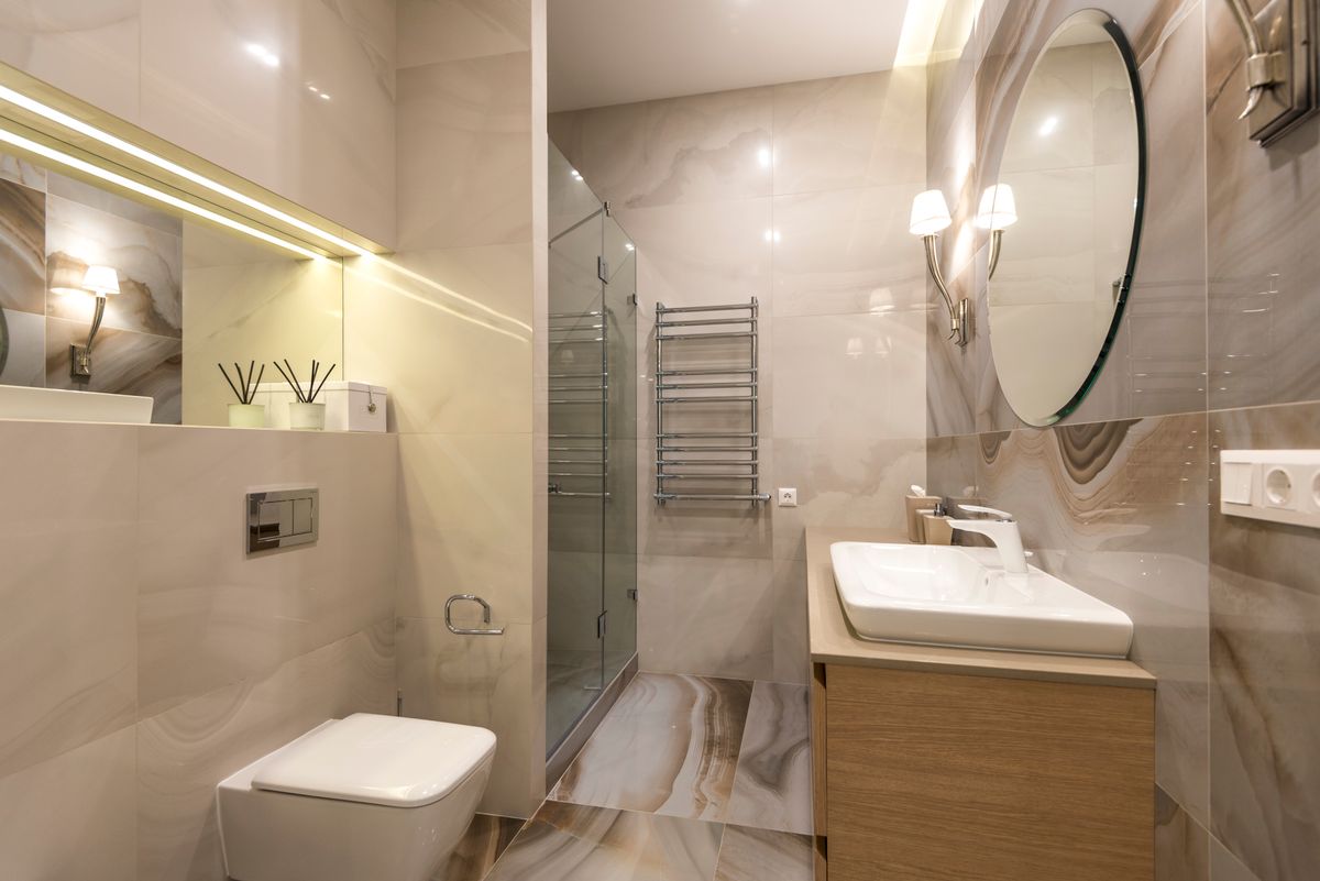 A warm, marble-tiled bathroom floor with a glass shower