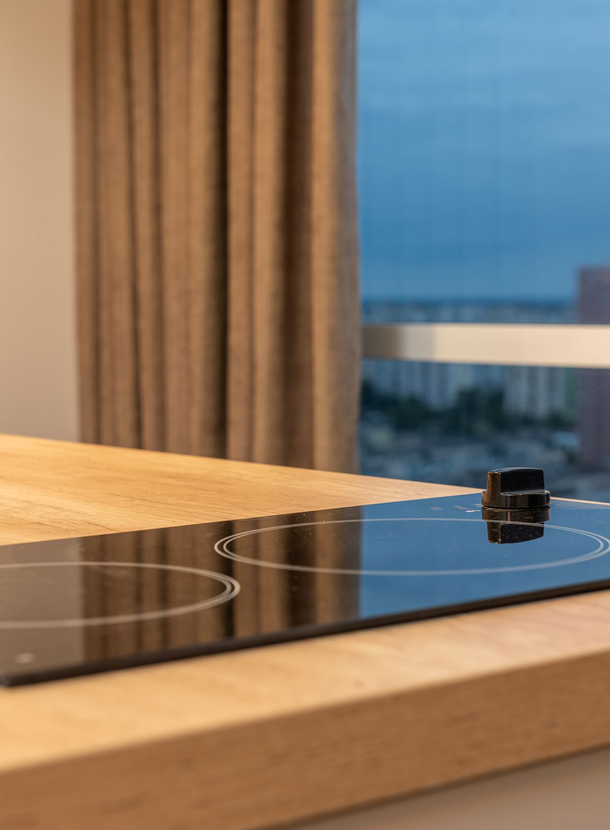 A black glass induction cooktop set into a warm wood countertop