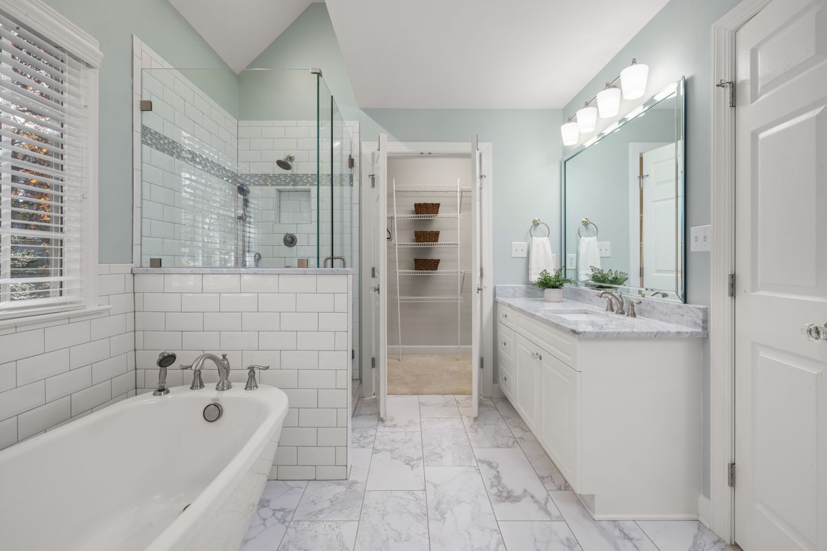 A dated bathroom in an older Bay Area home made over with white subway tile, a glass shower, and a classic soaking tub