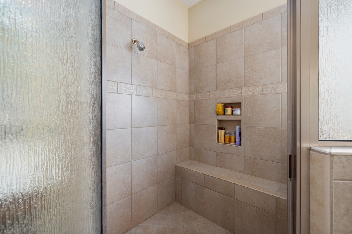 A tiled shower with a built-in bench in a made-over older bathroom