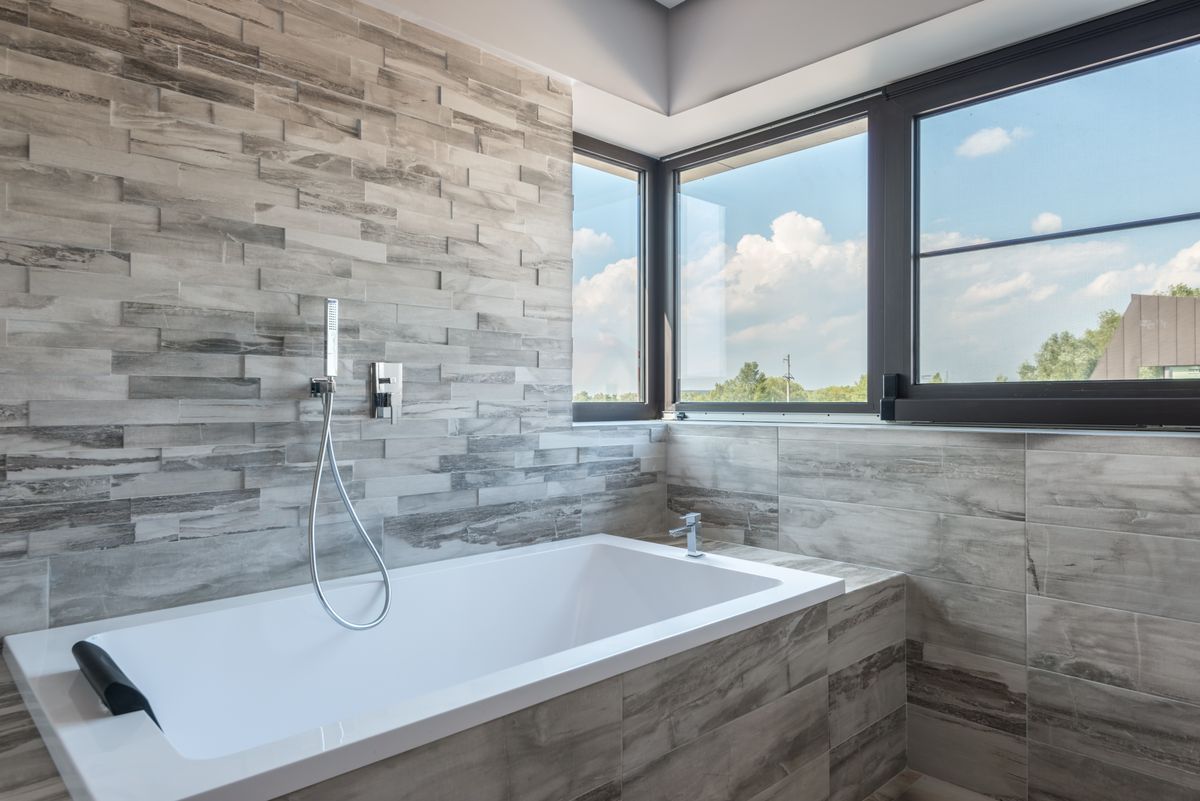 A soaking tub set beside bright corner windows
